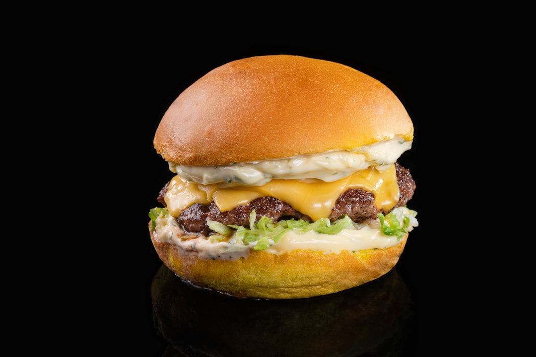 a-cheeseburger-with-meat-and-lettuce-on-a-black-background-vkgmu8ubb0q
