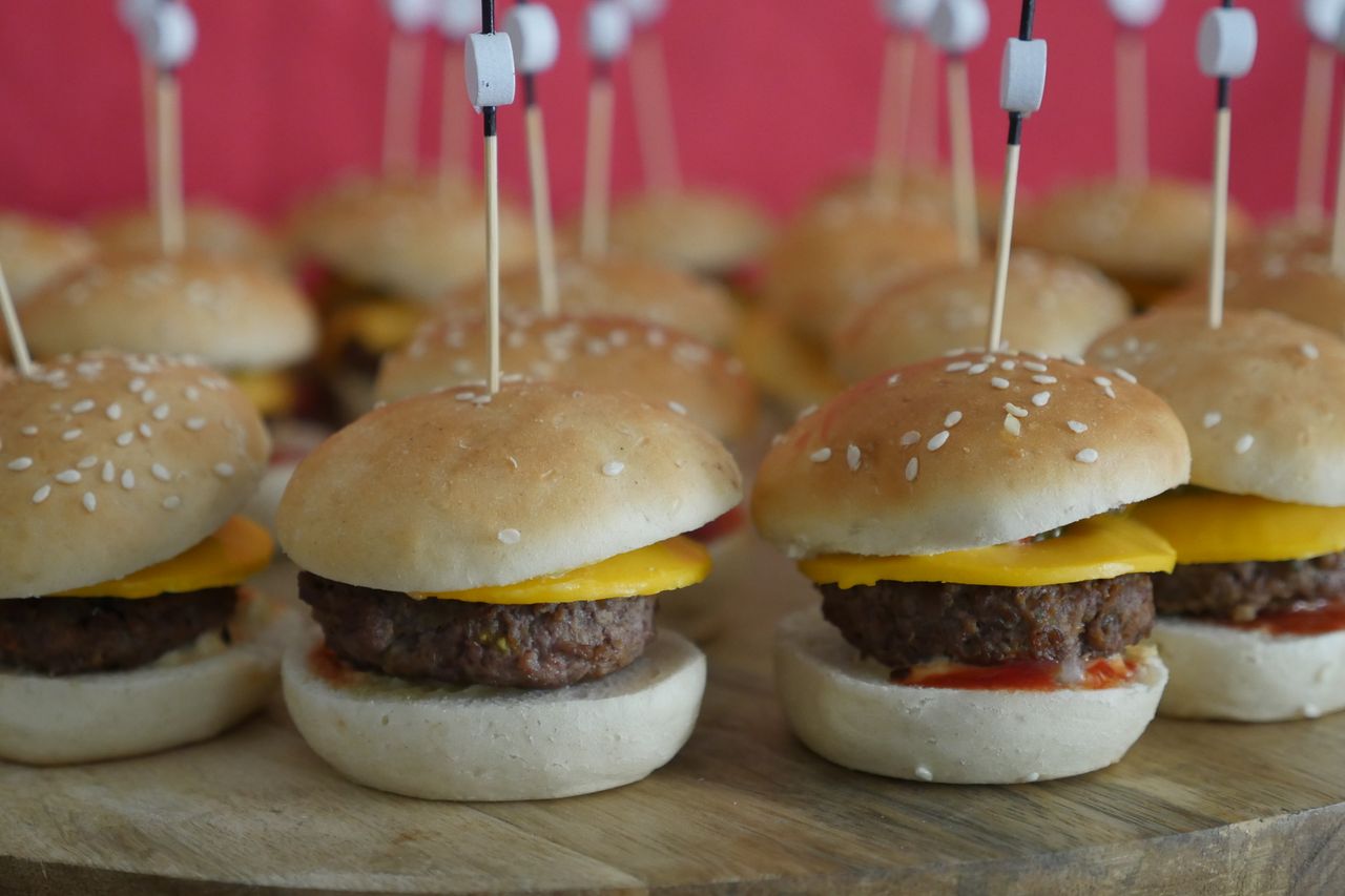 Delicious mini cheeseburgers with sesame buns and cheese, perfect for parties.